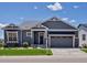 Charming one-story home featuring manicured lawn, gray siding, stone accents, and an attached two-car garage at 10258 W Coal Mine Pl, Littleton, CO 80127