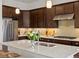 Bright kitchen featuring stainless steel appliances, a large island, dark wood cabinets, and modern fixtures at 10258 W Coal Mine Pl, Littleton, CO 80127