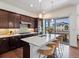 Modern kitchen featuring stainless steel appliances, dark wood cabinets, island with seating, and backyard view at 10258 W Coal Mine Pl, Littleton, CO 80127