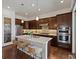 Open kitchen featuring stainless steel appliances, dark wood cabinets, and a large island with seating at 10258 W Coal Mine Pl, Littleton, CO 80127