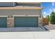 Attached two car garage has carriage doors, stone accents, and a private driveway at 11330 Pacific Peak Ct, Parker, CO 80134