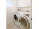 Efficient laundry room with modern white appliances, tiled floor, and white cabinetry for storage at 2685 S Acoma St, Denver, CO 80223
