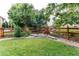 Well-maintained backyard with lush green grass, mature trees, wooden fence, and tasteful decor at 13241 Heart Lake Way, Broomfield, CO 80020