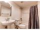 Bright bathroom featuring a pedestal sink, toilet, and a bathtub with shower, accented by a dark shower curtain at 13241 Heart Lake Way, Broomfield, CO 80020