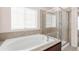 Bright bathroom with bathtub, shower, and tile surround with a large window at 5032 S Valdai Way, Aurora, CO 80015