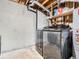 Unfinished basement laundry area with concrete walls, exposed ceiling, and modern gray washer and dryer at 15642 E Eldorado Dr, Aurora, CO 80013