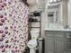 Bathroom with a sink, toilet, mirror, shelves, and shower curtain with a cherry pattern at 15642 E Eldorado Dr, Aurora, CO 80013
