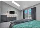 Spacious main bedroom with natural light from window views, a mounted TV, and gray modern furnishings at 9671 W Chatfield Ave # B, Littleton, CO 80128