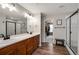 Well-lit bathroom featuring double sinks, wood cabinets, and a glass-enclosed shower at 27790 E 9Th Pl, Aurora, CO 80018