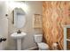 Charming powder room featuring a pedestal sink, decorative wallpaper, and a stylish round mirror at 27790 E 9Th Pl, Aurora, CO 80018