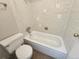 Bathroom featuring a toilet, a tub with tiled walls and wood look vinyl flooring at 9650 Huron St # 23, Thornton, CO 80260