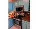 Galley kitchen featuring blue cabinets, stainless steel range, butcher block countertops, and modern microwave at 6700 W 11Th Ave # 205, Lakewood, CO 80214