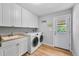 Laundry room featuring front loading washer and dryer, sink, cabinets and door to the outside at 8896 W Prentice Ave, Littleton, CO 80123
