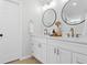 Bathroom with dual vanity, round mirrors, sleek faucets, and a white color scheme at 30484 Chisholm Trl, Elizabeth, CO 80107