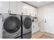 Well-lit laundry room featuring side-by-side washer and dryer and white cabinets for storage at 30484 Chisholm Trl, Elizabeth, CO 80107