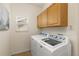 Laundry room featuring a side-by-side washer and dryer, tile floor, and wood cabinets at 2573 S Troy Ct, Aurora, CO 80014