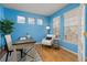 Office space with blue walls, hardwood floors, three windows, desk and seating, and lots of natural light at 2573 S Troy Ct, Aurora, CO 80014