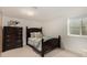 This is a bedroom with a large, dark wood dresser, a bed and a window in the basement at 374 Holly St, Denver, CO 80220
