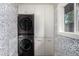 This laundry room features a stacked washer and dryer, white cabinets and patterned wallpaper at 374 Holly St, Denver, CO 80220