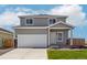 Two-story home featuring gray siding, white trim, a two-car garage, and a well-maintained front lawn at 48229 Shetland Dr, Bennett, CO 80102