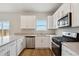 Modern kitchen features white cabinets, stainless steel appliances, and light countertops at 48229 Shetland Dr, Bennett, CO 80102