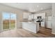 Bright, open kitchen featuring white cabinets, stainless steel appliances, and a sliding glass door to the backyard at 48229 Shetland Dr, Bennett, CO 80102