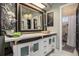 Stylish bathroom vanity with a large mirror, marble countertop, and ornate wood-framed mirror to the shower entrance at 14707 E Wagon Trail Dr, Aurora, CO 80015
