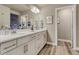 Bright bathroom featuring double sinks, white cabinets, granite counters, and wood-look flooring at 1734 Peak Prairie Ln, Monument, CO 80132