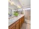 Well-lit bathroom featuring double sinks, wood cabinets, a walk-in shower, and tan tiling at 84 Inca St, Denver, CO 80223