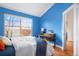 Bedroom with blue walls, hardwood floors, and a bright window at 84 Inca St, Denver, CO 80223