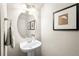 Cozy powder room with a pedestal sink, oval mirror, and tasteful wall decor at 84 Inca St, Denver, CO 80223