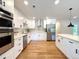 Modern kitchen boasts stainless steel appliances, sleek white cabinets, and gleaming hardwood floors at 9451 E Evans Pl, Denver, CO 80231