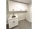 Updated laundry room with modern white cabinets, dark hardware, gray tile flooring, and utility sink at 9451 E Evans Pl, Denver, CO 80231
