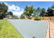 Wide angle shot of a private tennis court with lush green lawn and tree-lined privacy fence at 9451 E Evans Pl, Denver, CO 80231