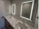 Elegant bathroom featuring dual sinks with illuminated mirrors and a marble countertop on wood cabinetry at 2330 Eliot St # 1, Denver, CO 80211