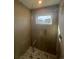 Modern shower with glass door, a marble tiled base, and a window provides natural light to the bathroom at 2330 Eliot St # 1, Denver, CO 80211