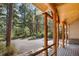 View of long log beams accenting the home's porch, with a view to surrounding trees and paved road at 26196 Rea Ave, Conifer, CO 80433