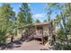 Charming home featuring a wooden deck, stone chimney, and natural surroundings with mature trees at 26196 Rea Ave, Conifer, CO 80433