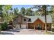 Charming two-story home features a stone chimney, a front porch with a wooden structure, and a well-maintained yard at 26196 Rea Ave, Conifer, CO 80433