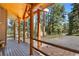 Inviting front porch featuring wooden beams, stone accents, and scenic views of the surrounding woods at 26196 Rea Ave, Conifer, CO 80433