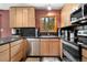 Modern kitchen with stainless steel appliances, dark countertops, and natural wood cabinets at 26196 Rea Ave, Conifer, CO 80433