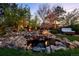A backyard oasis is complete with a tranquil waterfall, ambient string lighting, hot tub, and cozy fire pit area at 6402 E Cornell Ave, Denver, CO 80222