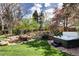 Backyard with a hot tub, waterfall, and pond surrounded by beautiful landscaping and trees at 6402 E Cornell Ave, Denver, CO 80222