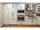 This kitchen features white cabinets, stainless steel appliances and a patterned tile backsplash at 6402 E Cornell Ave, Denver, CO 80222