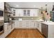 Bright kitchen featuring white cabinets, modern appliances, wood floors and beautiful pendant lights at 6402 E Cornell Ave, Denver, CO 80222