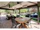 Enjoy outdoor living on this covered patio with a ceiling fan, fireplace, dining set, and serene backyard views at 6402 E Cornell Ave, Denver, CO 80222
