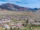 Picturesque aerial view showcasing homes alongside a golf course, set against a backdrop of rolling hills and red rock formations at 16226 River Haven Way, Morrison, CO 80465