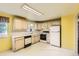 Eat-in kitchen featuring white appliances, tile backsplash, and light wood cabinets at 7542 Otis St, Arvada, CO 80003