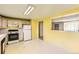 Eat-in kitchen with white appliances, yellow walls, window view to living room and side door at 7542 Otis St, Arvada, CO 80003