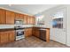 Well-lit kitchen with stainless steel appliances, warm wood cabinetry, and tile flooring at 2983 Fulton St, Denver, CO 80238